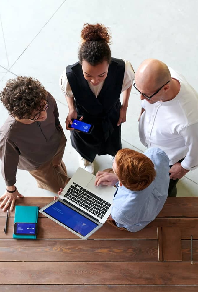 Equipo colaborando alrededor de un portátil y varios dispositivos